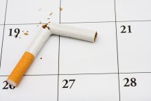 A broken cigarette on a calendar background, quit smoking now